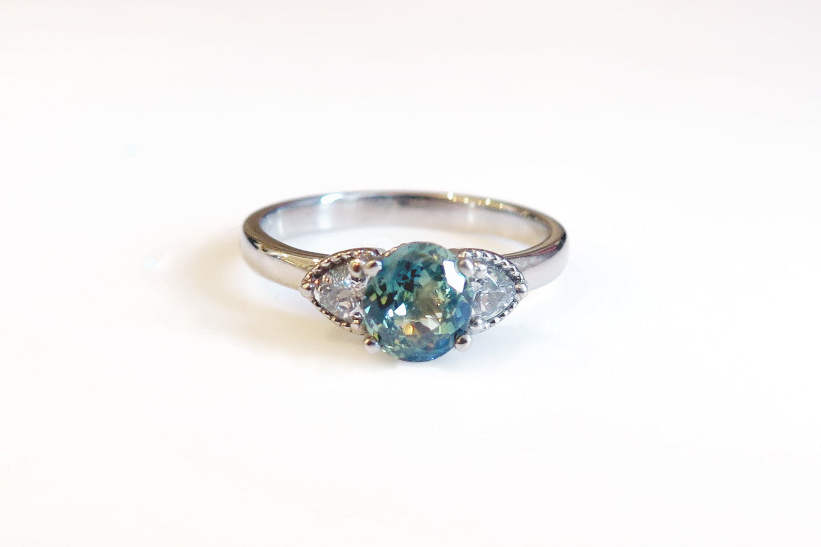 White gold engagement ring with a lagoon blue sapphire with white sapphires