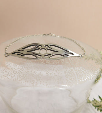 Deco Bracelet: Sterling silver symmetrical art deco bracelet with sterling silver chain, sitting on a glass pillar on a beige background