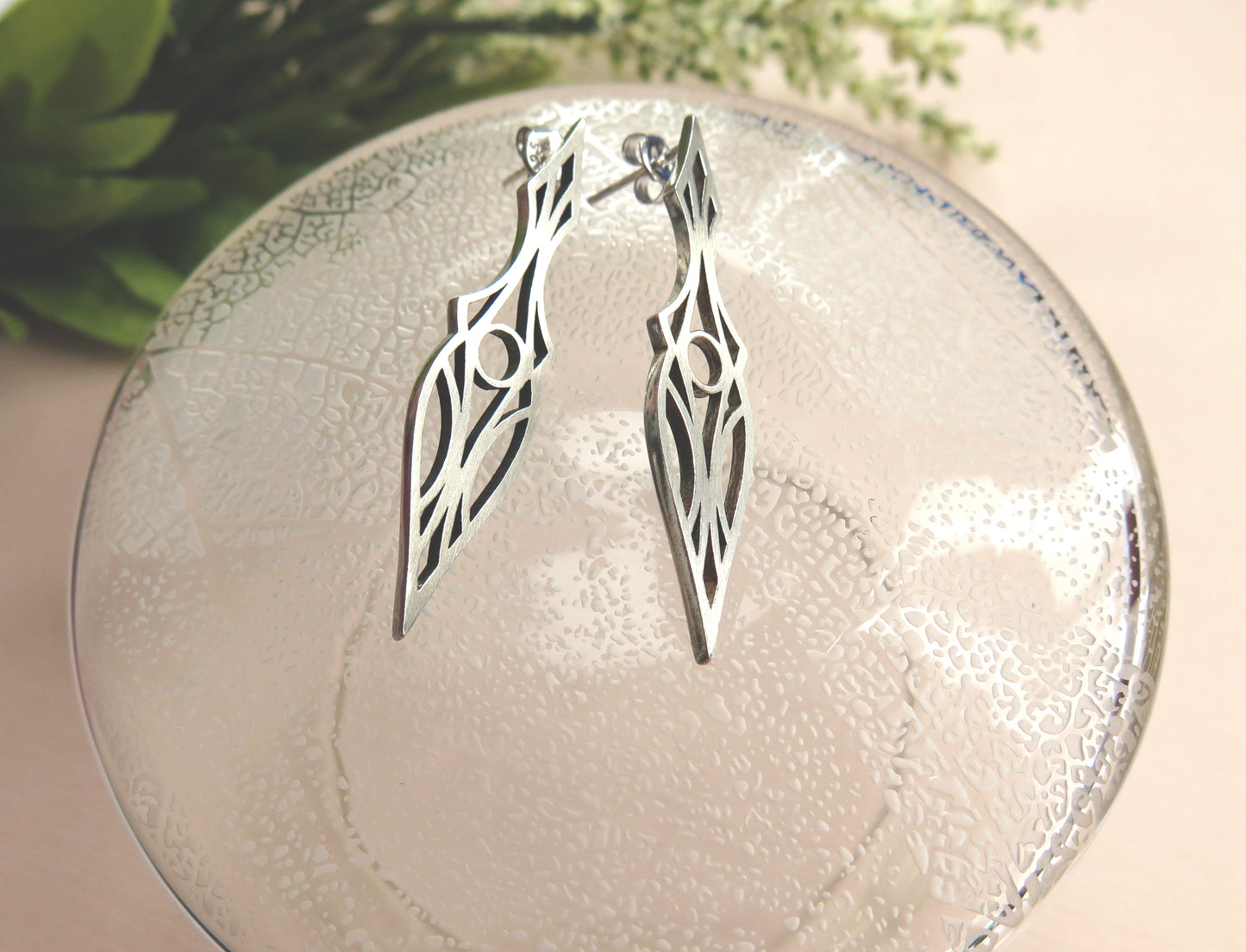 Art Deco stud earrings on a glass plate. Symmetrical and geometric modern design.