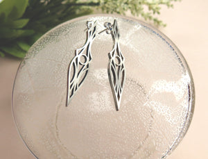 Art Deco stud earrings on a glass plate. Symmetrical and geometric modern design.