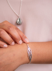 Sterling silver art deco mirrored teardrop bracelet on a model's wrist with art deco fig necklace in the background