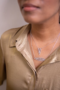 Model in a gold top wearing a sterling silver art deco symmetrical teardrop necklace and matching teardrop pendant necklace.