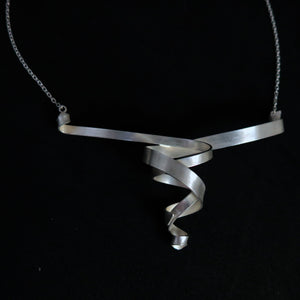 A modern sterling silver helix spiral ribbon pendant necklace on a black background.