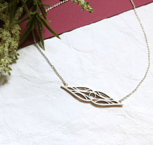 Load image into Gallery viewer, Art deco double teardrop symmetrical sterling silver necklace in high-sheen brushed finish oxidized for contrast. On a silver chain. On white and burgundy textured paper and a sprig of flowers.
