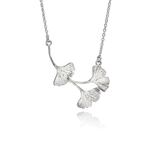 A sterling silver necklace made up of three small, textured ginkgo leave in an assymetric design. The necklace is on a white background